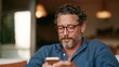 © Z A C - Man with glasses, beard, and mustache using a smartphone.