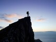 © aziseptian - Silhouette of a hiker standing on a mountain peak at twilight