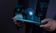 © sarach - Artificial intelligence and cloud computing concept with businessman hand holding tablet displaying glowing AI brain, cloud network, gears, and digital data graph on dark background.