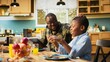 © DC Studio - African American dad multitasks on a tablet while chatting with his son and serving breakfast to his family in the kitchen; homemade food, togetherness and joyful bonding shape the morning meal.