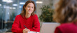 © perfectlab - Young woman in red sweater attentively listening and taking notes during a casual meeting with colleague