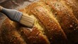 © Palmesrk - Close-up of freshly baked bread being brushed with melted butter, highlighting golden crust and herbs