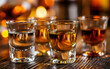 © Oleksiy - Alcohol consumption and social drinking, shot glasses with clear and amber liquor on a dark wooden bar counter