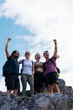 © Nikola Spasenoski - Group of friends celebrating on a mountain summit after a hiking trip, smiling and raising arms in outdoor adventure