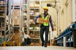 © Drazen - Full length of worker carrying package while working in distribution warehouse.
