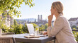 © MohamadMaliq - Geschäftsfrau mit Laptop auf Terrasse mit Blick auf München