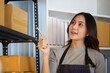 © Natee Meepian - Asian woman checking inventory stock on shelf for small e-commerce business