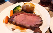 © jeafish - Tender slices of roasted beef served on a clean white plate, accompanied by wholesome side dishes of roasted potatoes, sweet carrots, and vibrant green broccoli for a hearty, gourmet meal.