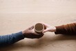 © AdPremium - Diverse hands passing and sharing a handcrafted ceramic cup over a natural wooden table