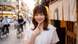 © Jesse_4160 - Happy young Japanese woman smiling and pointing at her chin on a busy Tokyo street in the evening with blurred bokeh background