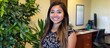 © ragil - Portrait of a Smiling Young Professional Woman in a Modern Bright Office with Indoor Plants