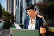 © Davor - Businesswoman reviewing documents at outdoor cafe with laptop and coffee