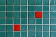 © Ade - Teal and red square tiles form a grid with light grout
