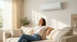 © Zaiseefa - On a hot summer day, a woman enjoys fresh cool air and relaxes on a sofa near a window conditioner.