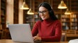 © BZXO - Distance education tech e learning concept featuring a happy young woman in glasses using a laptop in a library.