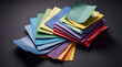 © Zhiming - This artistic arrangement features a vibrant stack of colored paper sheets in various hues, creating an appealing contrast against the dark background, perfect for creative projects.