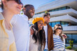 © CarlosBarquero - Cheerful friends enjoy a walk together in a clean modern residential area with contemporary buildings, sharing a relaxed social travel moment.