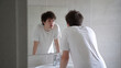 © 123sasha - Young man looking at himself in bathroom mirror