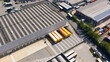 © Amazing Aerial - San Giuliano Milanese, Italy - 04 September 2026: Aerial view of the DHL Express facility with yellow delivery trucks parked at the loading bays of a large industrial warehouse.