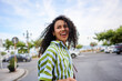© Alvaro Lavin/Stocksy - Young woman with curly hair smiling on urban street