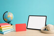 © Ziku - Digital learning tablet with blank screen, colorful school books and globe on desk, online education concept with headphones
