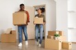 © Prostock-studio - Joyful Black Couple Smiling While Carrying Boxes Together In Their New Home, Preparing To Move In. Young Man And Woman In Their 20s Making New Memories Together In Modern Living Room. Moving Concept.