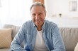 © Prostock-studio - Smiling Elderly Caucasian Man Enjoying Moment At Home, Sitting On Couch With Positive Emotion, Reflecting Joy And Happiness In Cozy Living Room Environment. Lifestyle Concept.