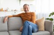 © Prostock-studio - Smiling Elderly Caucasian Man Sitting Comfortably On Couch In Living Room, Enjoying Relaxation And Comfort, Embracing A Peaceful Atmosphere At Home. Lifestyle Concept.