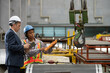 © BESTIMAGE - Owner boss manager assistant secretary inspection inspecting in warehouse inventory storage Female supervisor holding pendant remote controller operating overhead crane hook beside male manager