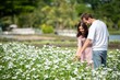 © BESTIMAGE - Romantic couple enjoying and looking white flower field together emotional bonding moment between couple outdoors. Happiness two people male smiling and female touching flowers in garden