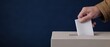 © Nattapun - Detailed close up of a hand placing a ballot into a voting box during the electoral process