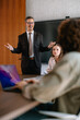 © kerkezz - Confident Businessman Leading Presentation in Modern Office Meeting With Colleagues and Team