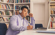 © Prostock-studio - Focused Asian Male Student In His 20s Sitting At Home Office Desk With Laptop, Taking Notes And Listening With Headphones, Engaged In Study Process. Online Learning And Education Concept.
