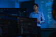 © ultramansk - A curly haired male graduate engineer in light blue shirtsleeves holds his tablet against his chest while listening to a question inside a modern digital office