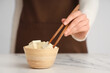 © Pixel-Shot - Woman with bowl of tasty tofu cheese on table, closeup