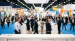 © Wannaeka - Dynamic blurred scene of people discussing at exhibitor booths in a busy trade show.