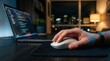 © Wannaeka - Close-up of a hand using a white mouse for digital work with a laptop in the background.