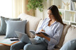 © PheelingsMedia - Telecommuter taking notes in agenda watching laptop content
