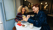 © Julia - Friends sharing a smartphone at a cozy cafe