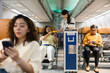 © akarawit - Flight attendant serving drinks from a trolley in an airplane cabin as passengers sit and use smartphones; economy seating and aisle view create a realistic inflight travel scene.