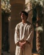 © Trendy Graphics - A young man in ancient egyptian tunic standing outdoors with pillars and palm trees