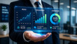 © DEBI - This image shows a businessman holding a digital holographic dashboard that displays key business and marketing analytics
