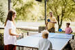 © BGStock72 - Family fun at the outdoor ping pong table beside a serene lake