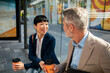 © Davor - Business colleagues chatting over coffee at urban bus stop
