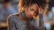 © Evarelle - Injured Black woman wearing neck brace holding her forehead in pain. Female worker suffering from whiplash and headache in office
