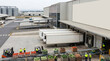 © AI_ID - Industrial warehouse distribution center with freight trucks at loading docks and workers managing fresh produce logistics