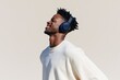 © Iryna - Joyful young man wearing dark headphones looking upward with neutral backdrop for wallpaper or banner design and lifestyle use