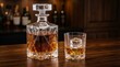 © Casandra - Crystal decanter and glass filled with amber whiskey and ice cube on wooden bar