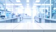 © HecoPhoto - Out of focus contemporary laboratory room with clean white table foreground, glass partitions, shelves, scientific instruments and bright blue background