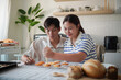 © matinee - Asian couple decorating freshly baked cookies with colorful icing.
